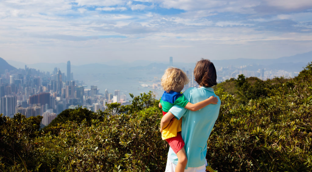 Família caminhando nas montanhas de Hong Kong olhando a poluição atmosférica sobre a cidade