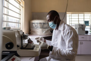 A lab scientist works on a microtome machine in Nigeria: cervical cancer prevention and treatment. Health-care facility electrification can support the use of advanced diagnostic tools.