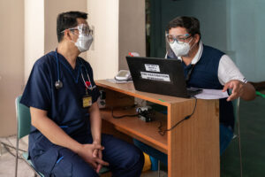 Two doctors do intake at a computer as COVID-19 vaccines arrive